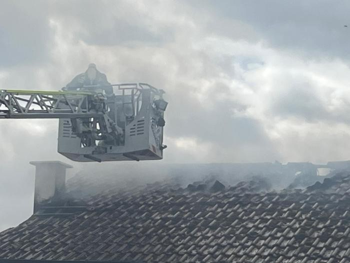 Feuerwehr im Einsatz mit der Drehleiter am brennenden Haus