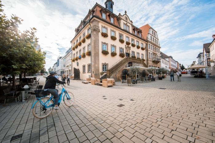 Eine Radfahrerin fährt in der Fußgängerzone am historischen Rathaus vorbei.