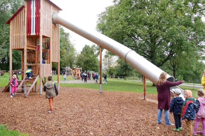 Blick auf den Spielplatz Dahenfelder Bahnhof mit großer Röhrenrutsche im Vordergrund 