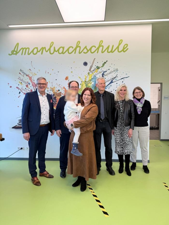 Gruppenbild mit den Ehrengästen der Einsetzungsfeier vor einem Plakat der Amorbachschule Foto: privat