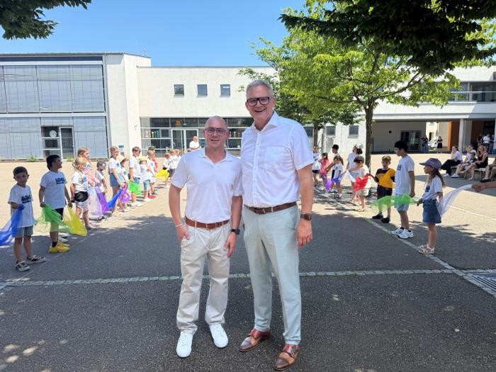 OB Steffen Hertwig steht mit Sven Martig auf dem Schulhof. Im Hintergrund bilden Kinder ein Spalier. Foto: privat