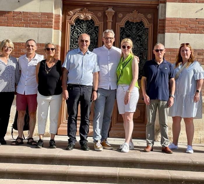Neckarsulmer Delegation und der Bürgermeister Bousquet vor dem Rathaus in Carmaux Acht Personen stehen vor der Tür eines Gebäudes für ein gemeinsames Foto.