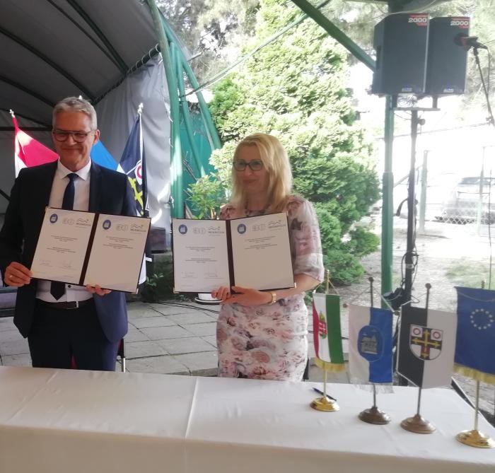 Oberbürgermeister Steffen Hertwig und Bürgermeisterin Dr. Ottilia Györi halten jeweils zwei Urkunden vor sich ausgebreitet.