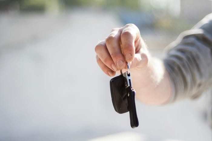Eine Person streckt einen Autoschlüssel aus.