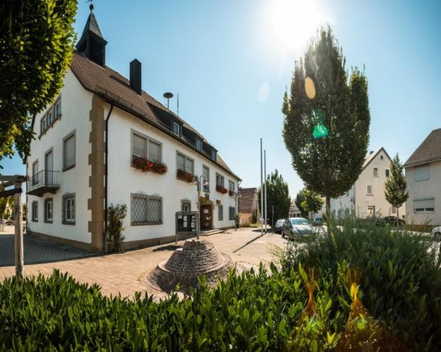 Verwaltungsstelle Obereisesheim. Im Vordergrund sind ein Brunnen und Bäume zu sehen.