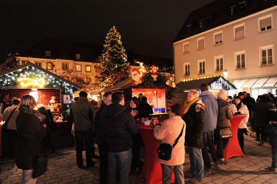 Besucher vor beleuchteten Markthütten beim Weihnachtsmarkt auf dem Marktpkatz  