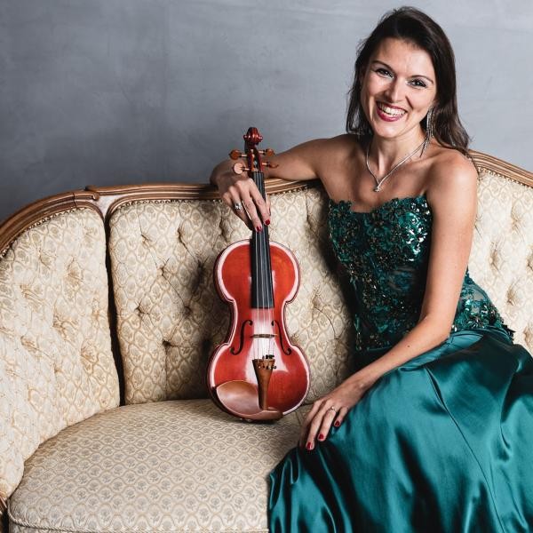 Porträtfoto von Amy Lungu mit Violine auf dem Sofa  
