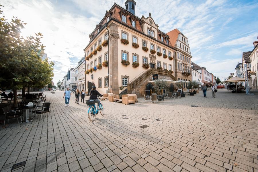 Eine Radfahrerin fährt in der Fußgängerzone am historischen Rathaus vorbei.