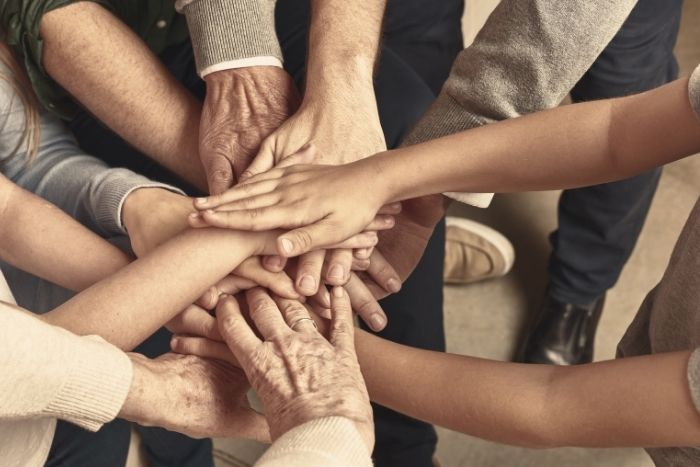 Hände unterschiedlicher Personen kommen in der Bildmitte zusammen.