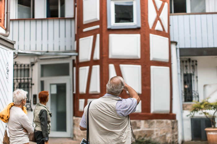 Ein Neckarsulmer Stadtführer zeigt Personen ein historisches Gebäude in der Neckarsulmer Innenstadt.