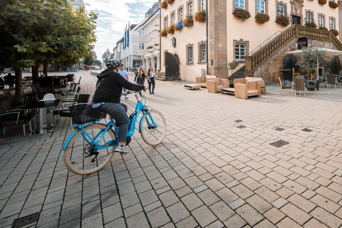 Radfahrerin fährt in der Innenstadt von Neckarsulm am historischen Rathaus vorbei.