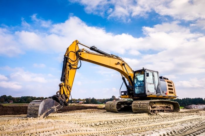 Foto: Adobe Stock Ein Bagger steht auf einer Baustelle auf einem sandigen Untergrund.