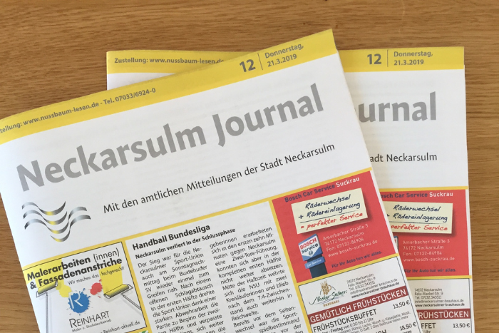 Zwei Neckarsulm Journale liegen übereinander auf einem Holztisch.