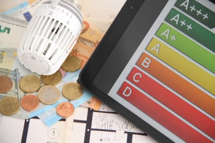 Ein Thermostat, Geldmünzen und -scheine sowie eine Energieverbrauchs-Übersicht liegen auf einem Tisch.s-