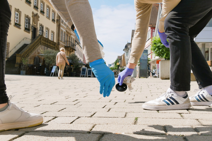 Zwei Menschen heben Müll auf