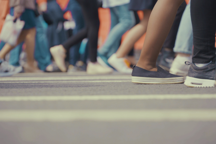 Viele Personen laufen auf einer Straße. Sie sind knieabwärts abgebildet.