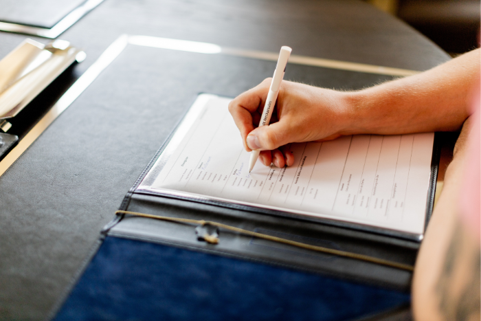 Eine Person hält einen Stift in der Hand und unterzeichnet ein Dokument.